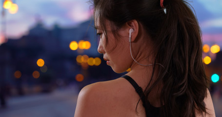 Profile view of young Asian athlete wearing earbuds near the in urban Europe