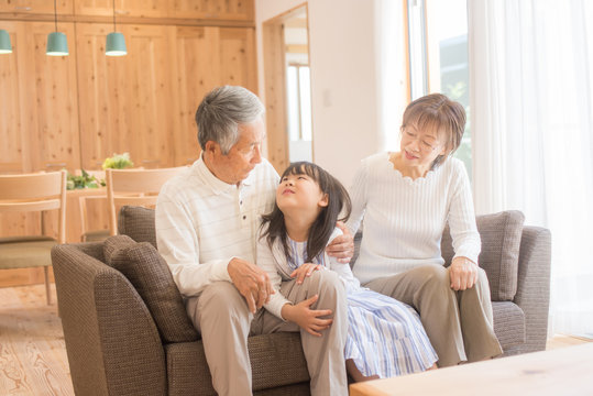リビングのソファでくつろぐ孫娘とシニア夫婦