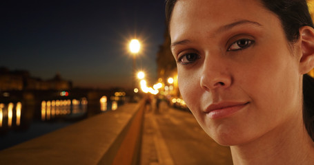 Close up portrait of pretty tourist woman on Florence street at night by river
