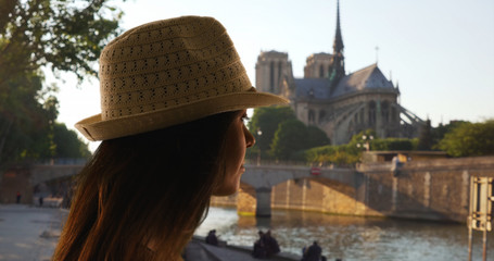 Side view of tourist woman near Notre Dame Cathedral looking out at the Seine