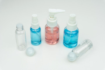 close up of the pink, blue and clear liquid containers on white background