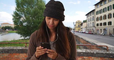 Obraz premium Woman in Florence texting and listening to music with smartphone