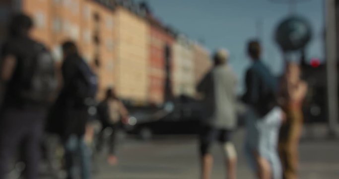 Blurred cars and people walking and bicycling at an intersection in central Stockholm.