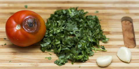 rotten tomatoes and dill, garlic on a cutting board
