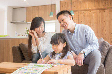 リビングで勉強する娘を優しく見守る父親と母親