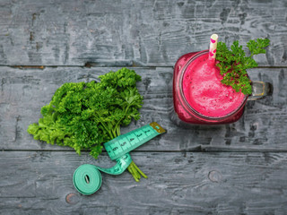 Fresh beetroot smoothie, measuting tape, two beet and parsley on black wooden table. The concept of dietary natural food. Vegetarian cuisine. Flat lay.