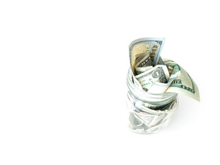 A view of a glass mason savings jar full of cash stuffed inside including singles, twenties and hundred dollar bills isolated on a white background.