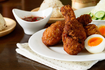 a plate of Asian fried chicken accompanied with hard boiled egg, steamed glutinous rice and spicy dipping sauce