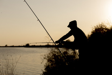 man is fishing at sunset