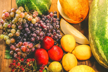 various summer and autumn fruits. watermelon. melon, peaches and grapes. lemon and lime. on a wooden table.