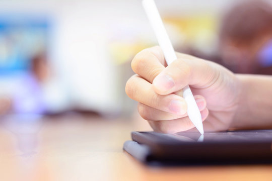 Hand hoding pen on tablet on blur background