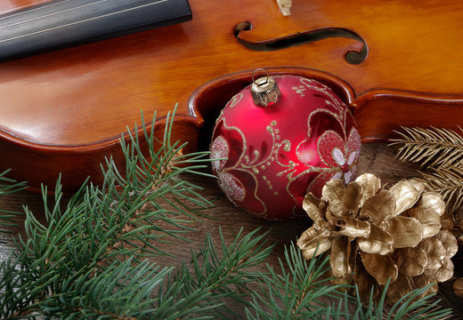 New Year background. New Year's ball, violin, branches of the Christmas tree and golden fir cones on a wooden table.