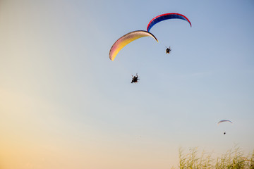 Guy flying on the clearly blue sky and wonderful beach by paramotor red kite, extreme activity port. feel freedom like birds. concept overcome the limits of  human physiology.