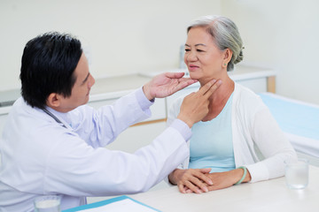 Obraz na płótnie Canvas Doctor examining throat of senior woman during regual check-up