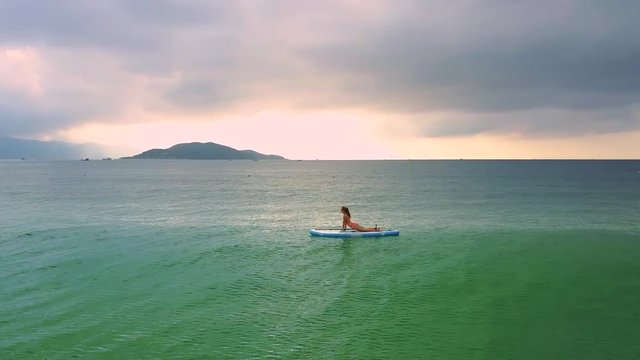 girl lies on paddleboard on stomach leaning against hands