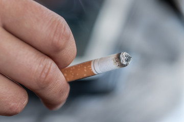 Female hand holding lit cigarette.