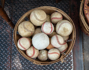 A basket of old weathered baseballs sitting outside on the street