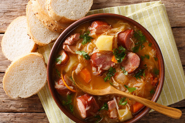 Delicious soup of sauerkraut with sausages and vegetables close-up in a bowl. Horizontal top view
