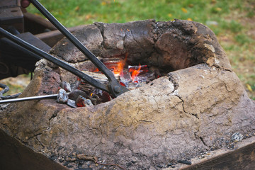 Medieval furnace with iron tongs, burning coals and fire in blacksmith forge