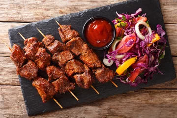 Foto op Aluminium Suya- Roast African spicy skewered beef kebab is served with fresh vegetable salad and ketchup close-up. Horizontal top view © FomaA
