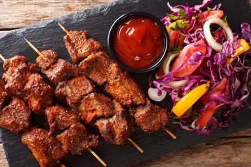Gordijnen African food: spicy suya kebab on skewers with fresh vegetable salad and ketchup close-up. Horizontal top view © FomaA