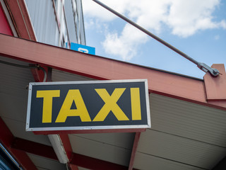 Yellow taxi sign hanging above outdoor waiting area