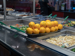 Oranges piled on a buffet table with various pastas 