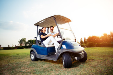 Couple in driving buggy on golf course