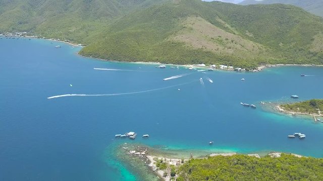 Aerial view sea ship sailing in bay on green island landscape. Sailing boat and parasailing in blue sea lagoon. Beautiful ocean view from flying drone.