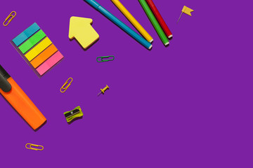 set of various school and office supplies lying diagonally on a purple background. free copyspace