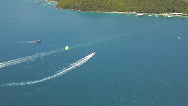 Parasailing in blue sea drone view. Aerial shot sailing boat in turquoise water in sea bay. Beautiful landscape blue lagoon and resort beach.