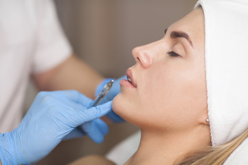 The cosmetologist makes injections of botulinum toxin in the lips of the patient. Cosmetology skin...