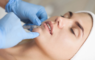 Fototapeta na wymiar The cosmetologist makes injections of botulinum toxin in the lips of the patient. Cosmetology skin care.