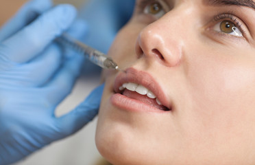 The cosmetologist makes injections of botulinum toxin in the lips of the patient. Cosmetology skin care. © lashkhidzetim