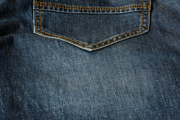 Close-up of a piece of blue jeans with orange stitches. Pocket close-up.