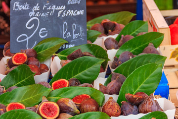 Ripe mediterranean purple figs on display with a handwritten chalkboard price tag at a local farmers market in Nice France