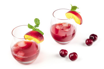Two vibrant red drinks with cherries on white