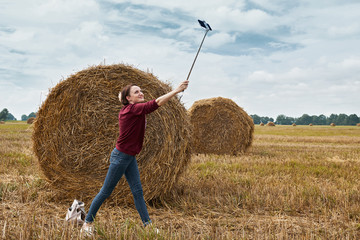 Naklejka na ściany i meble young girl makes selfie on smartphone on the background of haystack