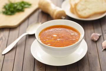 Chicken soup with vegetables and herbs in a white bowl on a wooden table