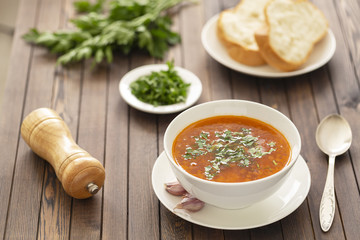 Chicken soup with vegetables and herbs in a white bowl on a wooden table