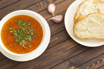 Chicken soup with vegetables and herbs in a white bowl on a wooden table