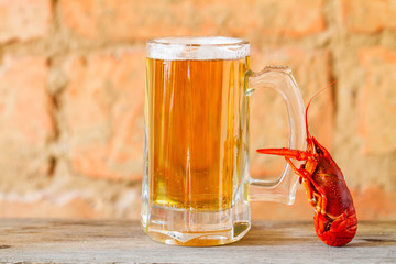Boiled red crawfish holds a beer mug cold. Closeup, selective focus, brick brown background