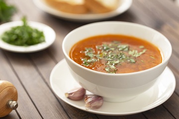 Chicken soup with vegetables and herbs in a white bowl on a wooden table