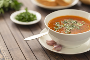 Chicken soup with vegetables and herbs in a white bowl on a wooden table
