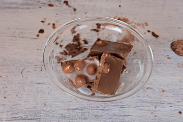 Sweet hazelnut chocolate in the glass bowl at light wooden background 