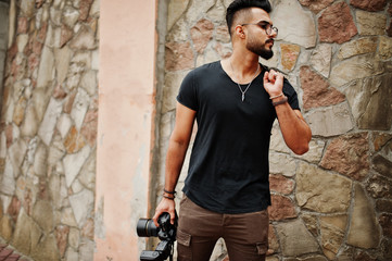 Awesome beautiful tall ararbian beard macho man photographer in glasses and black t-shirt with professional camera at hands.
