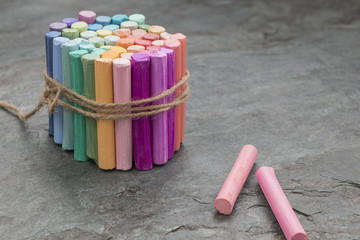 Bunch of colored pastel crayons with rose crayons aside on dark background with copy space. Art supplies. Selective focus