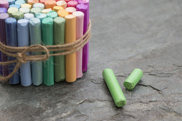 Green crayons and bunch of colored pastel crayons on dark textured background for art studio....