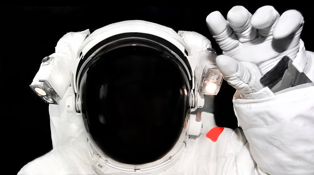 Astronaut in spacesuit raised his hand for a greeting. Spaceman close up in outer space. Elements of this image furnished by NASA