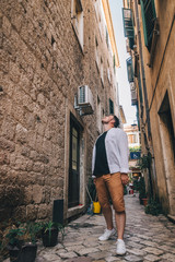 Obraz na płótnie Canvas young stylish man walking by tight Kotor street. Montenegro